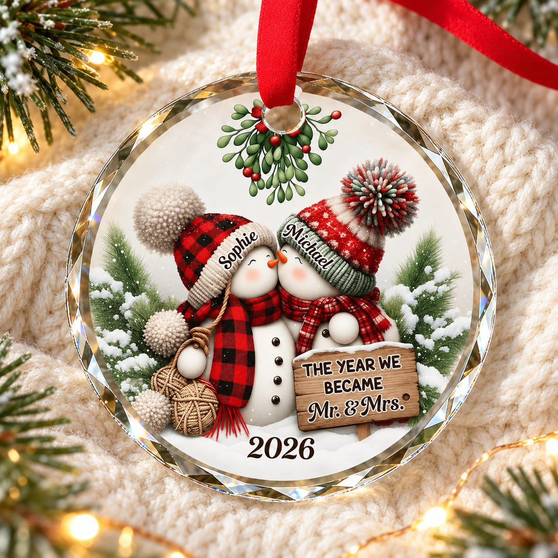 Our 1st Married Christmas Mr Mrs circle glass ornament lying flat on a cozy cream knit blanket with pine greenery