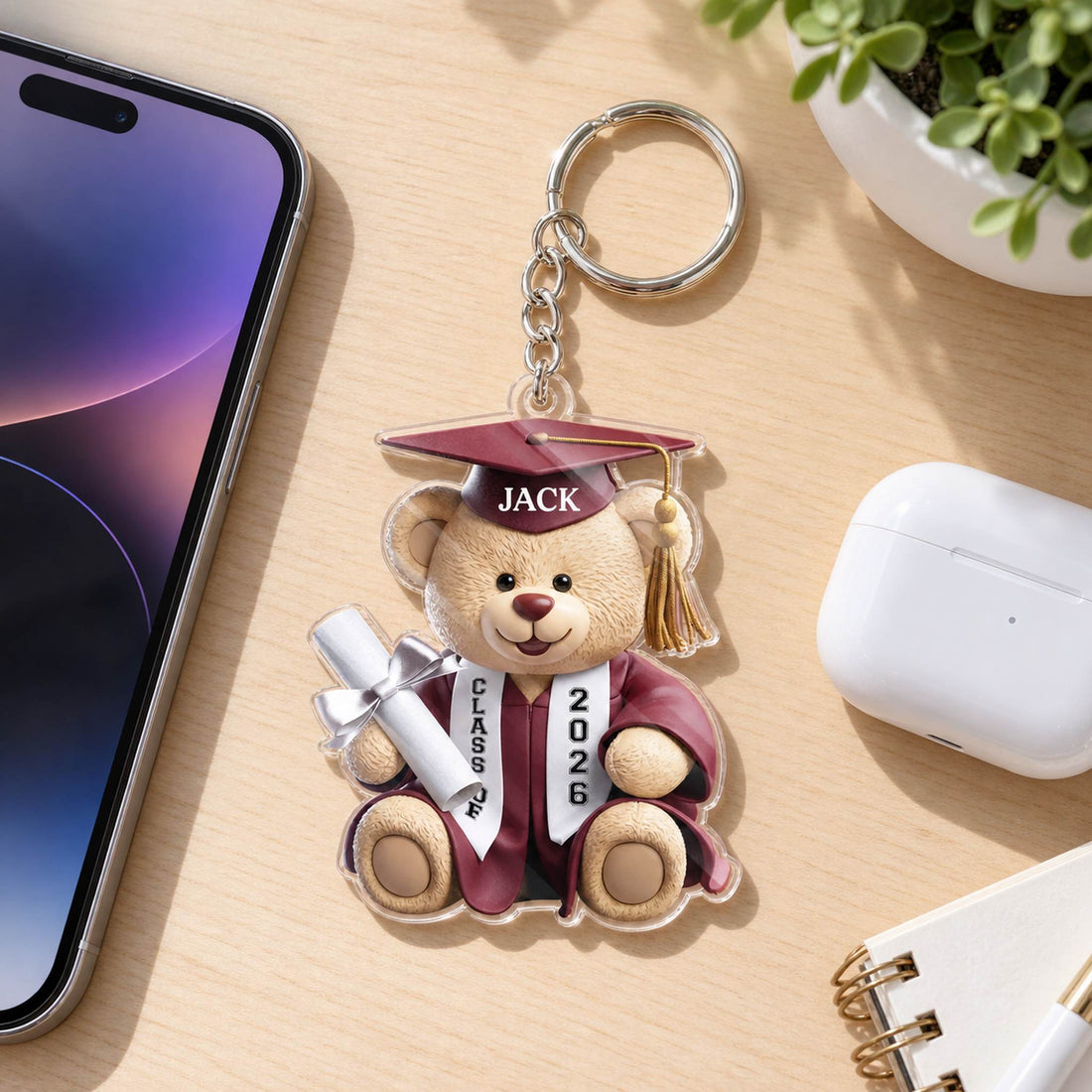 3.15 inch graduation bear acrylic keychain lying flat next to a smartphone for size scale