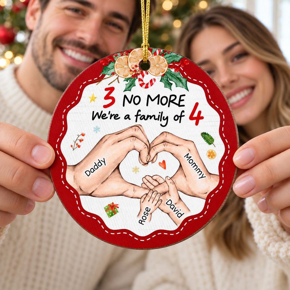 Young parents holding their personalized family of four wood Christmas ornament
