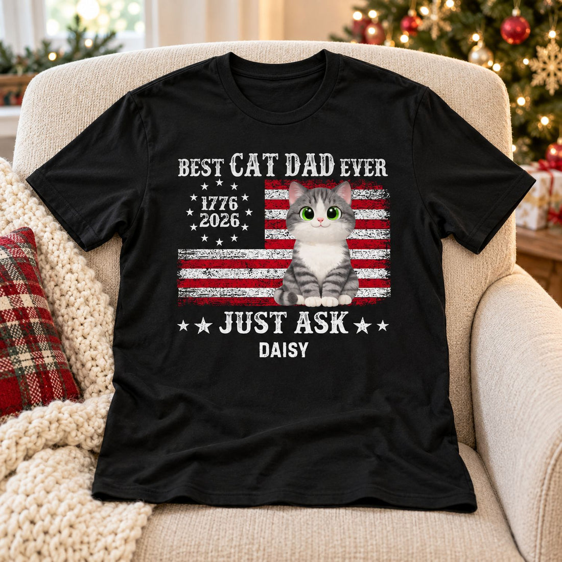 Personalized Cat Dad 250th anniversary t-shirt laid on an armchair by a Christmas tree