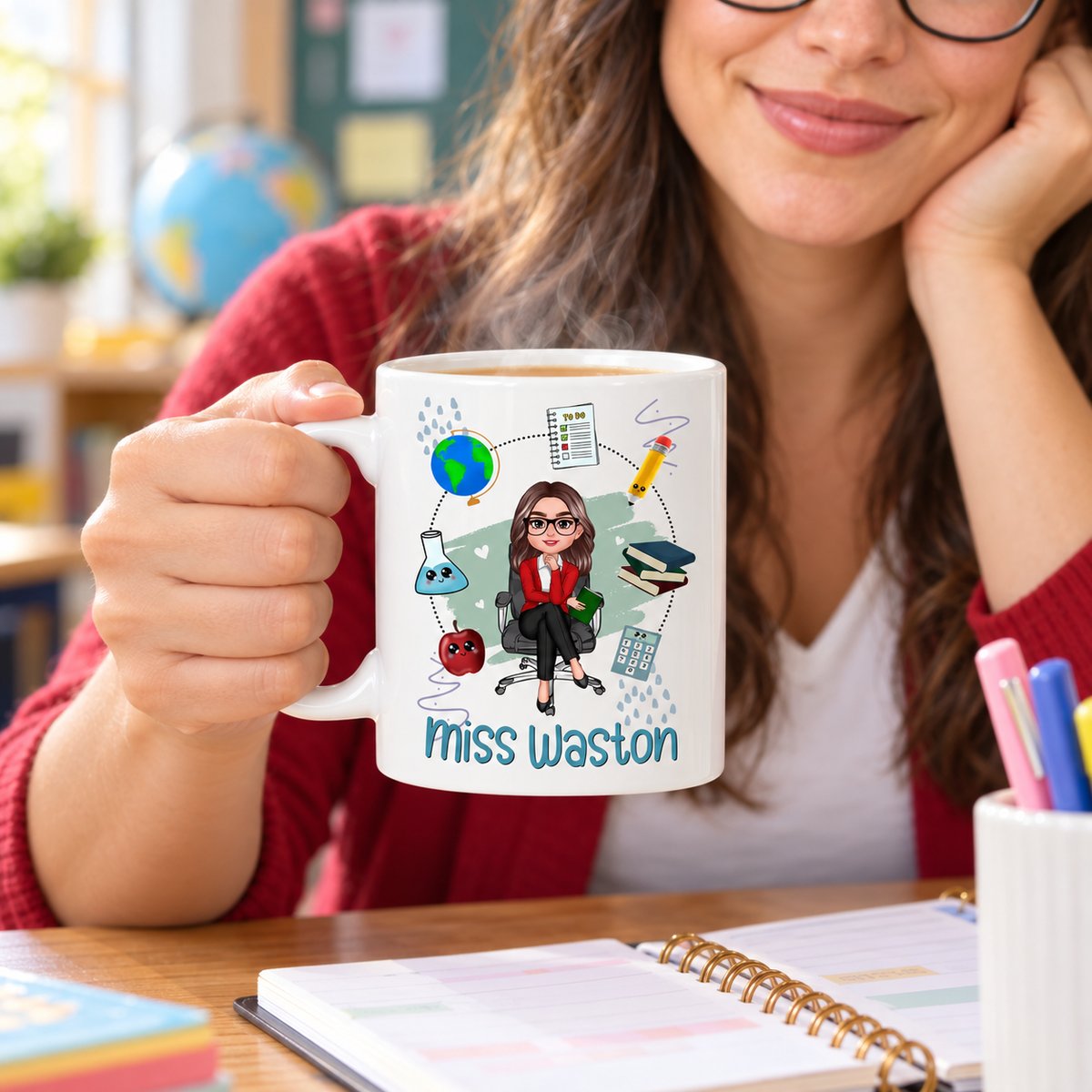 Personalized teacher ceramic mug held at a bright classroom desk with lesson planner