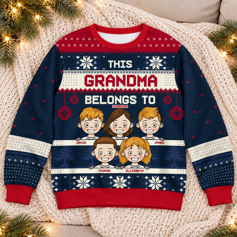 Personalized This Grandma Belongs To Christmas sweater laid flat with holiday greenery