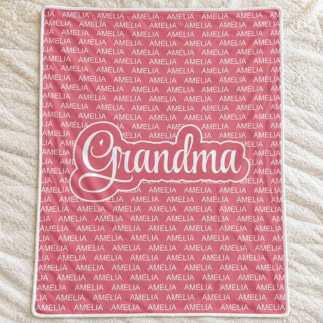 Personalized dusty rose Grandma blanket with repeated Amelia name spread flat on a cream bedspread