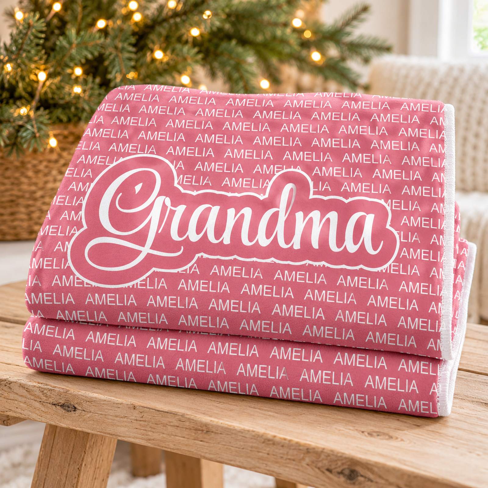 Folded personalized Grandma fleece blanket in dusty rose pink with holiday greenery in background