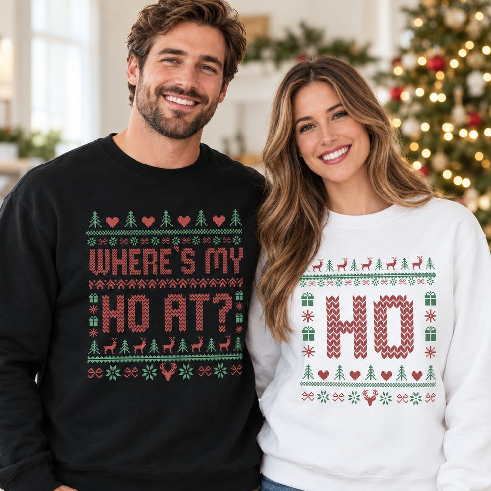 Couple wearing matching Wheres My Ho At and Ho ugly Christmas sweatshirts in front of a holiday tree