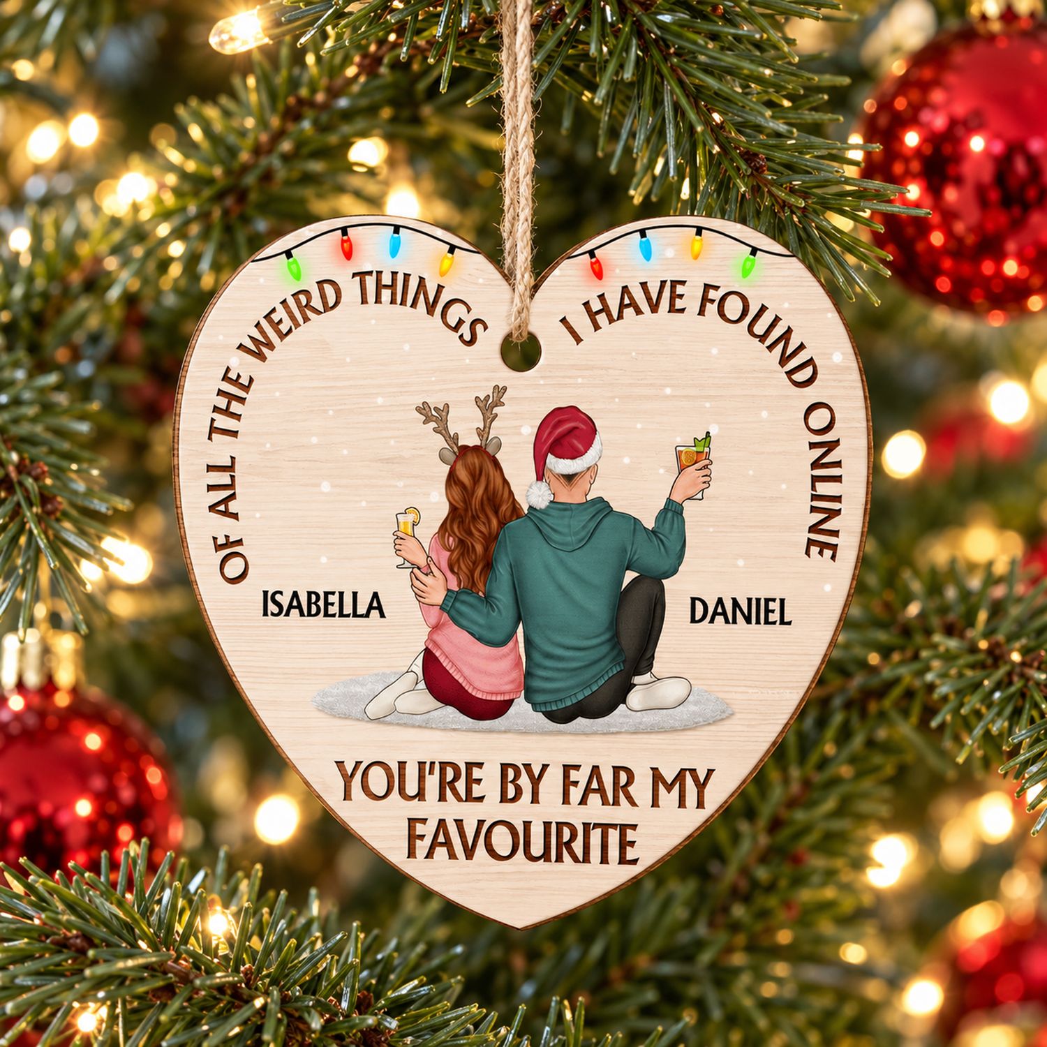 Personalized couple heart wooden ornament hanging on a Christmas tree branch with warm holiday lights